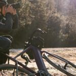 rowerzysta zatrzymał się i położył swój rower elektryczny ale zrobić zdjęcie w lesie